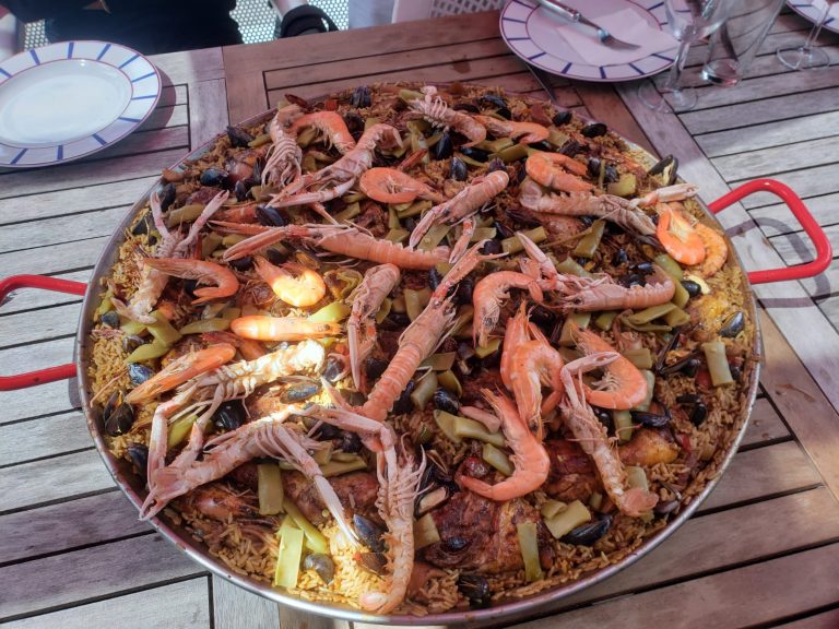 Grande paella aux gambas et moules servie sur une table en extérieur