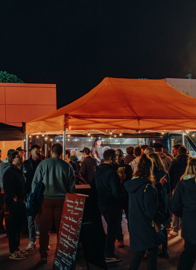 Soirée sous un barnum orange, foule autour du camion