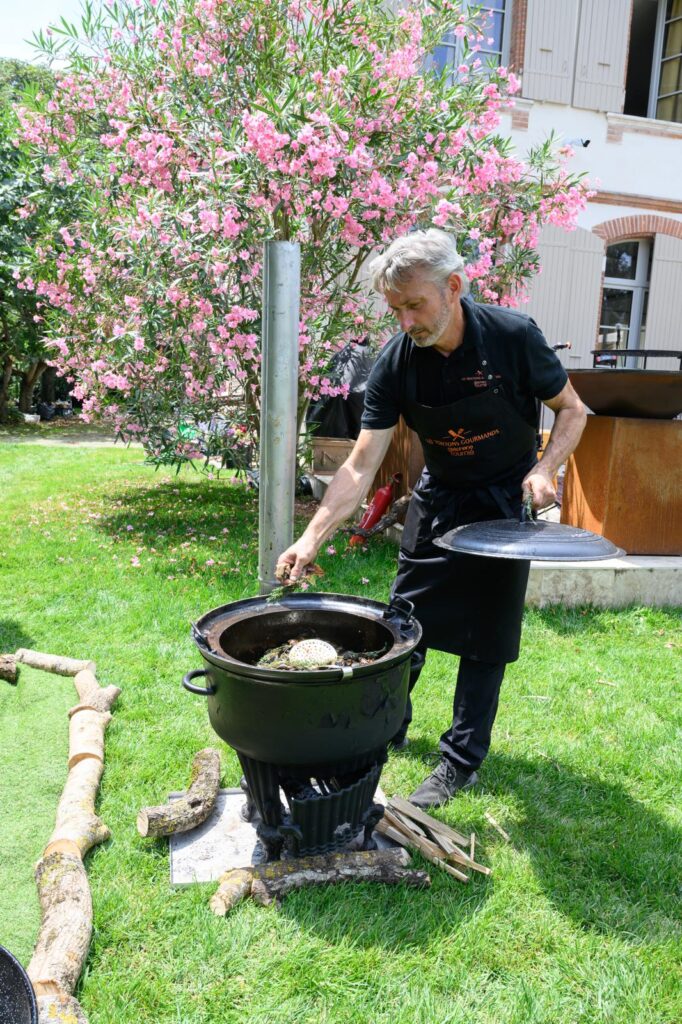 Le chef cuisine dans une marmite au feu de bois, dans un jardin