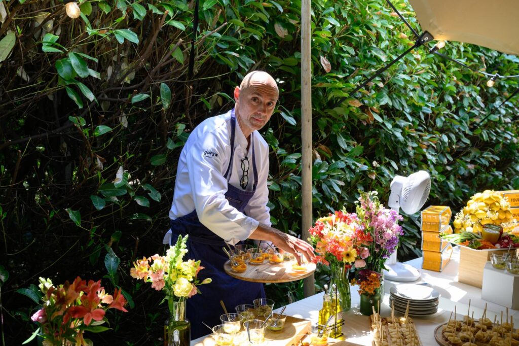 Le chef dresse un plateau sur un buffet fleuri, en extérieur