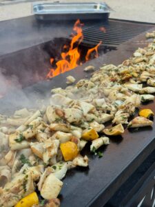Chipirons et citrons grillés sur la plaque du brasero, flammes au fond