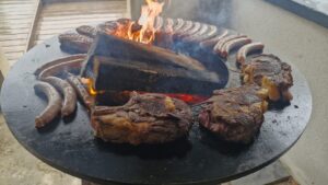 Entrecôtes et saucisses de Toulouse sur le brasero, bûches en flammes