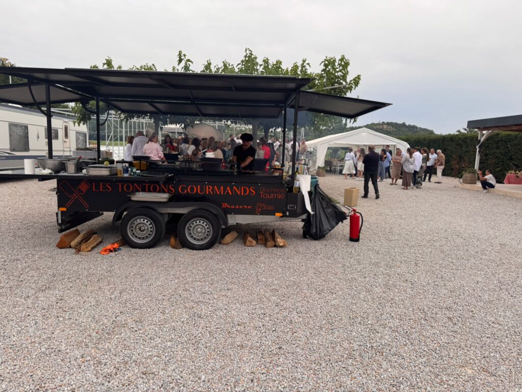 La remorque des Tontons Gourmands installée pour une réception, invités en arrière-plan